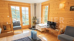 Una cabaña acogedora con paredes de madera, chimenea, sofá y televisor.