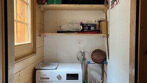 Un lavadero pequeño con una lavadora Siemens, un tendedero y una repisa con diversos objetos.