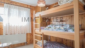 A bunk bed room with a wooden floor, a small table, and a radiator. - Appartement pour 5 personnes au rez-de-chaussée situé à seulement 300 mètres des pistes et bénéficia (St-Luc)