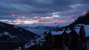 A mountainous landscape with snow-covered peaks and a village with traditional wooden buildings. - Duplex de 3,5 pièces (75 m2) pour 4-5 personnes très lumineux, situé en face de l’Office du tourisme (Chandolin)