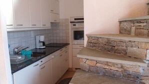 A kitchen with white cabinets, a stone countertop, and a built-in oven. - Duplex de 3,5 pièces (75 m2) pour 4-5 personnes très lumineux, situé en face de l’Office du tourisme (Chandolin)