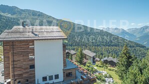 A modern building with a wooden facade and a balcony, surrounded by a mountainous landscape. - Situé au centre de Chandolin dans une petite résidence, proche de toutes commodités et du bus navett (Chandolin)