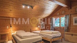 A wooden cabin with two single beds, a wooden dresser, and a window with curtains. - Situé au centre de Chandolin dans une petite résidence, proche de toutes commodités et du bus navett (Chandolin)