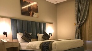 Een moderne slaapkamer met een groot bed, een nachtkastje, een wandlamp en een stadsgezicht schilderij.