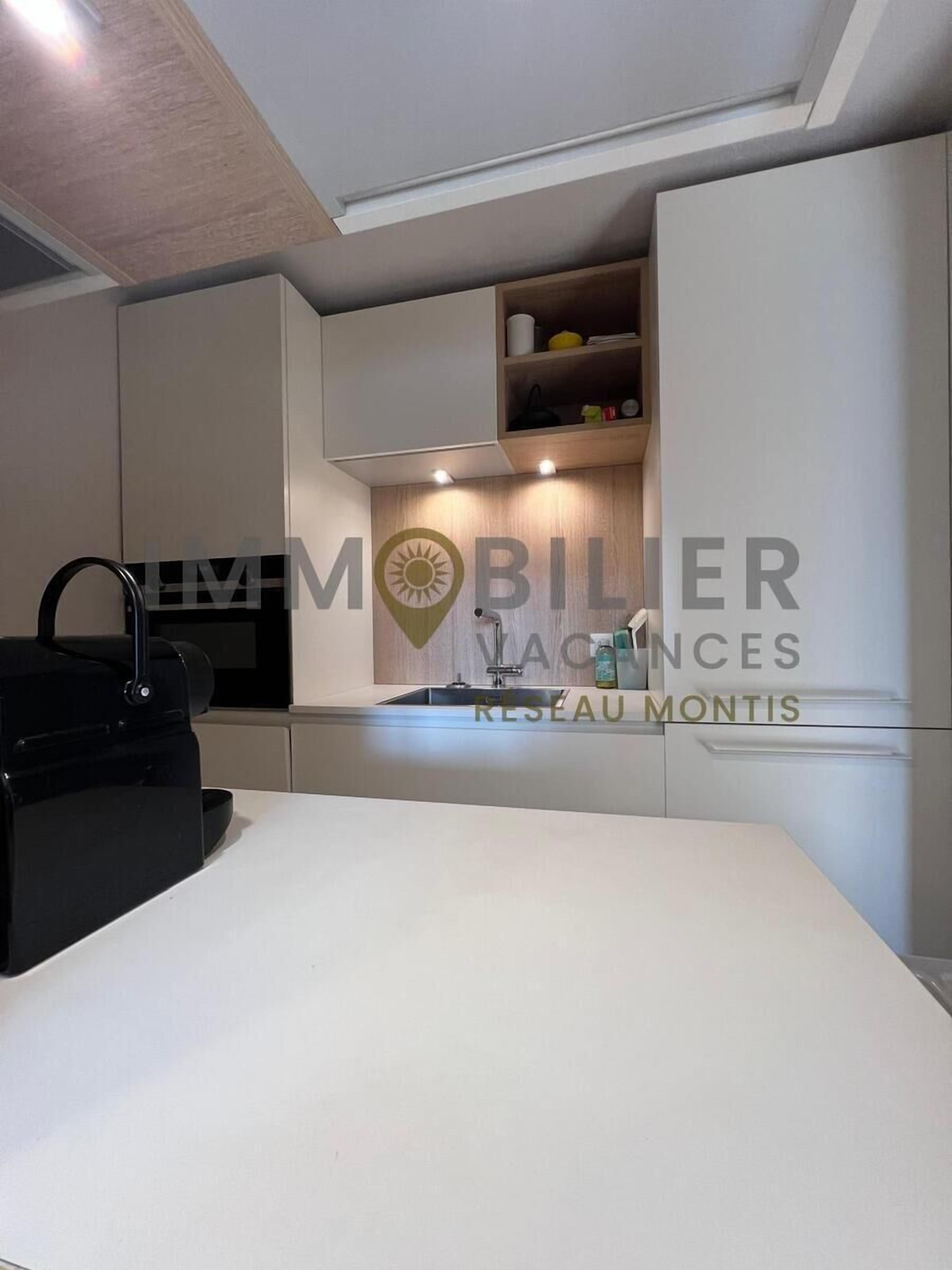 A modern kitchen with white cabinets, a black countertop, and a built-in sink.
