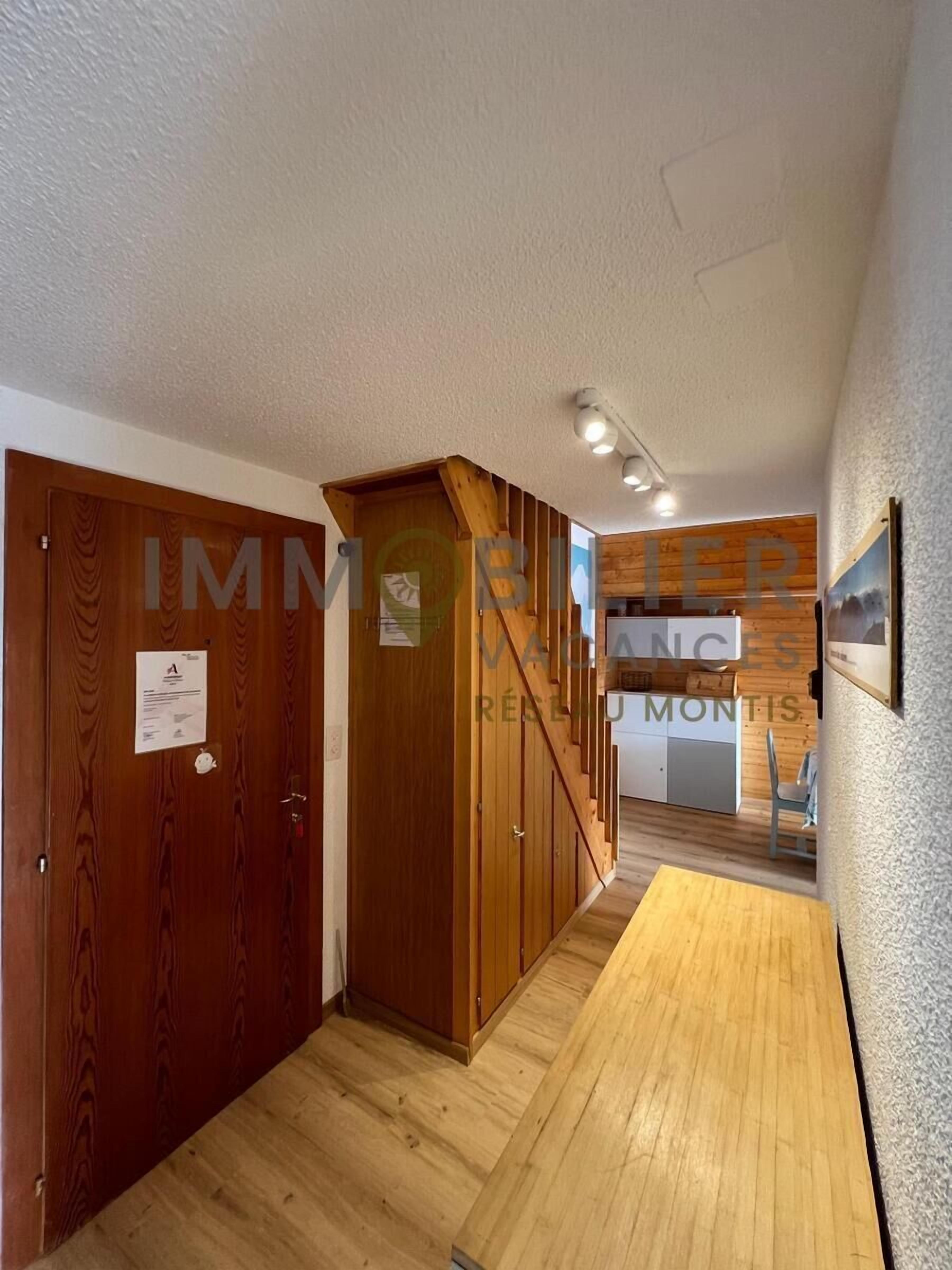 A hallway with wooden doors and a staircase.