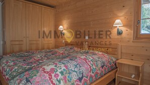 Una habitación con paneles de madera, una cama, dos lámparas fijadas a la pared y un armario de madera.