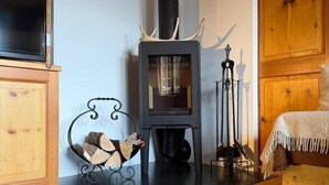 A cozy room with a wood-burning stove, a bed, and a TV.
