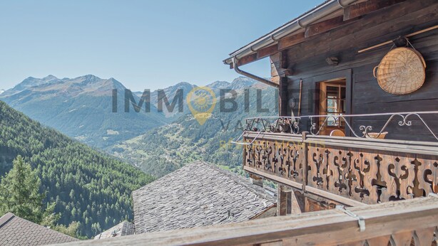 A wooden building with a balcony overlooking a mountainous landscape.