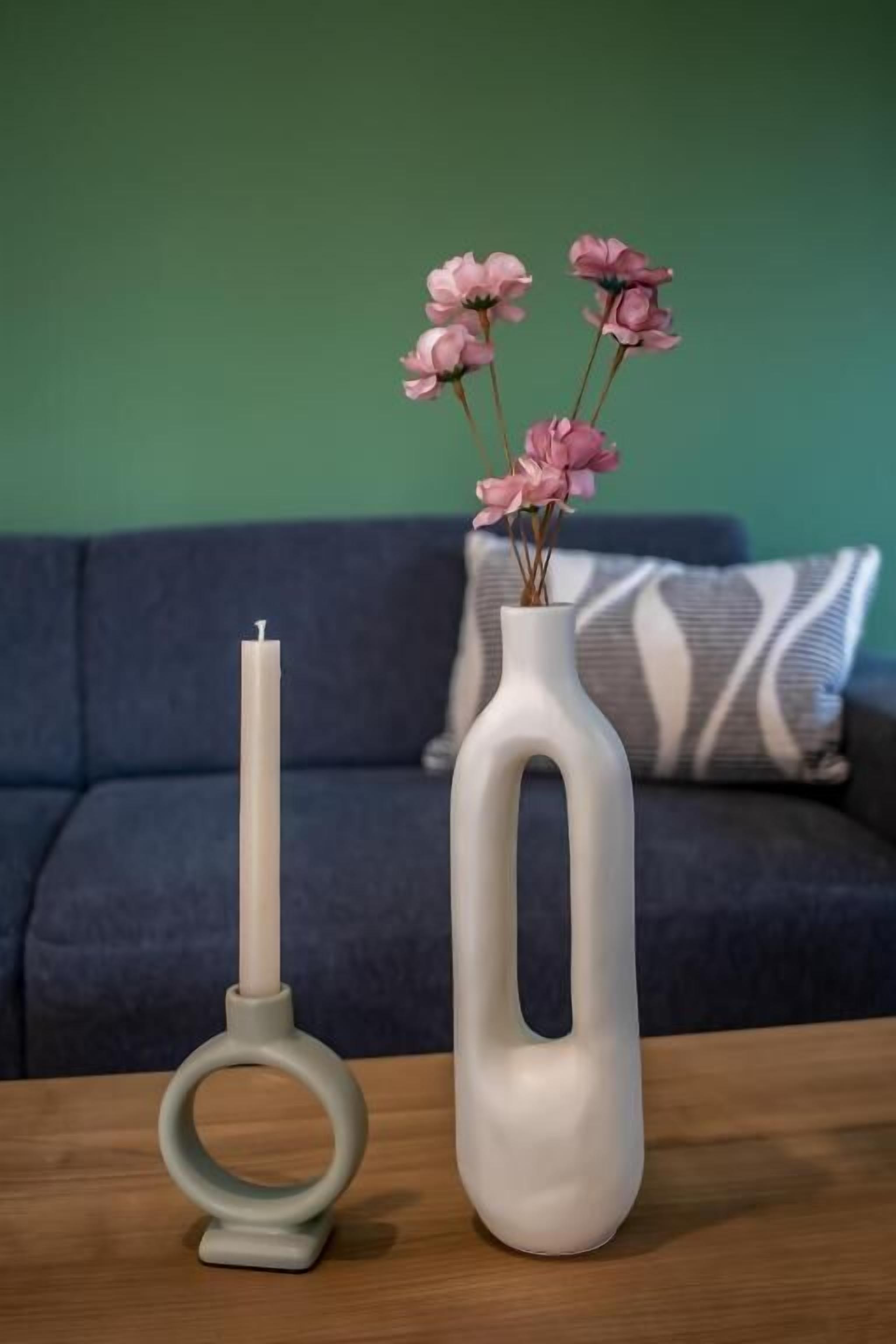 Una mesa con un candelabro blanco y un jarrón con flores rosas.