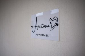 Een bordje met de tekst 'Anastasia's Apartment' op een effen muur.