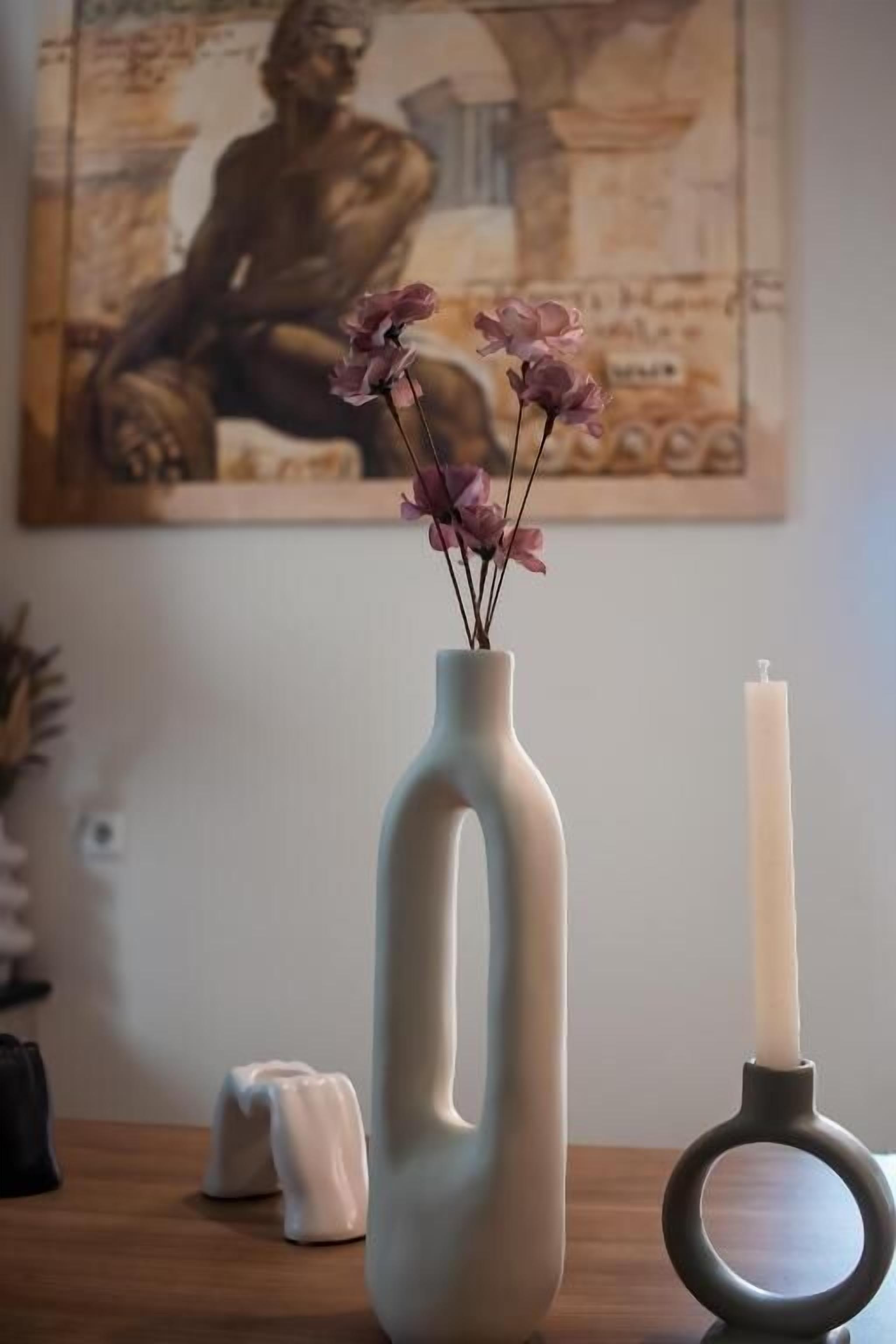 A vase with flowers and a candle on a table.