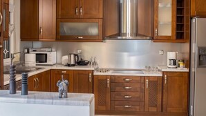 Una cocina con armarios de madera, una campana extractora de acero inoxidable, un microondas, una cafetera y un fregadero.