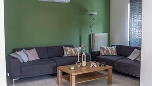 Una sala de estar con dos sofás grises, una mesa de centro de madera y una pared verde.