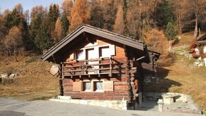 Une cabane en bois avec un toit en pente, une roue à l’avant et des fondations en pierre.
