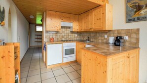 A kitchen with wooden cabinets, a tiled backsplash, a stove, and a sink. - Très beau duplex combles plein sud, vue splendide ! Aisément accessible, à l'entrée du village, à pr (St-Luc)