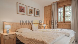 Una camera da letto con due letti, una testiera in legno, un comodino con una lampada e quadri appesi al muro.