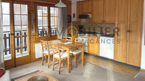Un interno in legno con un tavolo da pranzo, sedie, una cucina con mobili in legno e un'ampia finestra.