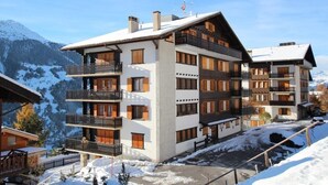 Un hotel a più piani con balconi, sullo sfondo di una montagna innevata.