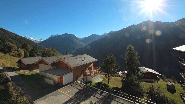 Un rifugio alpino con un ampio parcheggio e vista sulle montagne circostanti.