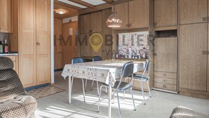 A dining area with a table set for four, surrounded by wooden cabinets and a hanging light fixture. - Spacious 2.5-room apartment with TV and Wi-Fi, south-west facing, with 2 large balconies, ideal for (St-Luc)