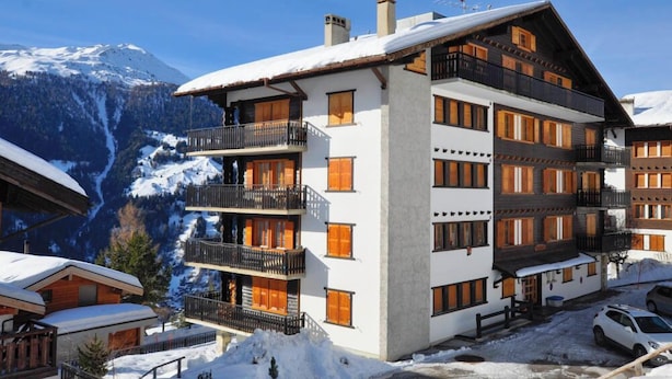 A multi-story hotel with balconies, a ski slope in the background, and a clear sky. - Spacious 2.5-room apartment with TV and Wi-Fi, south-west facing, with 2 large balconies, ideal for (St-Luc)