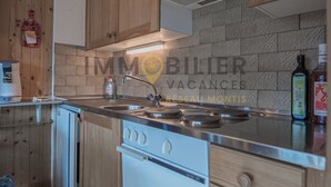 A modern kitchen with wooden cabinets, a stainless steel sink, and a built-in oven. - Spacious 2.5-room apartment with TV and Wi-Fi, south-west facing, with 2 large balconies, ideal for (St-Luc)