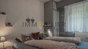 A bedroom with two beds, a nightstand, a lamp, and a wall with decorative items.