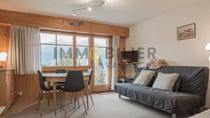 A cozy room with a dining area, a sofa, and a TV.