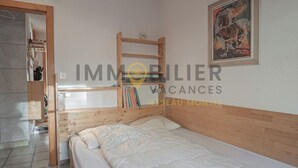 A bedroom with a bunk bed, a wooden headboard, a bedside table, a lamp, and a painting on the wall.