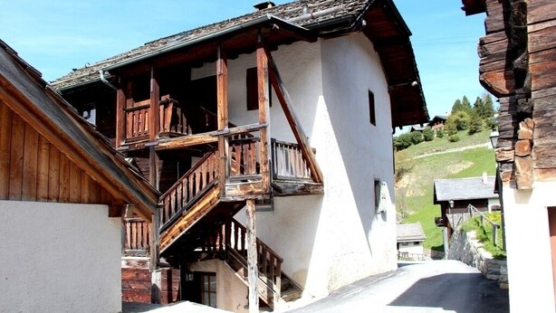 A traditional wooden building with a balcony and a staircase leading to the entrance. - In the heart of the old village of Chandolin, a charming, authentic apartment, entirely panelled in (Chandolin)
