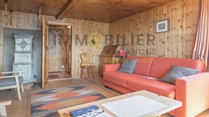 A cozy room with a wooden ceiling, a red sofa, a small table, and a patterned rug. - In the heart of the old village of Chandolin, a charming, authentic apartment, entirely panelled in (Chandolin)