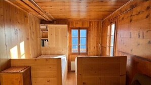 A cabin with wooden walls and floors, a small kitchenette, a window, and a sofa. - In the heart of the old village of Chandolin, a charming, authentic apartment, entirely panelled in (Chandolin)