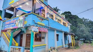 A two-story building with a sign indicating 'Ruby Lodge' and 'Rooms Available'. - Ruby Home Stay (Sagara)