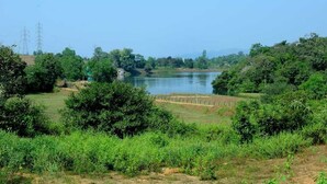 A serene landscape with a lake, surrounded by lush greenery and distant power lines. - Ruby Home Stay (Sagara)