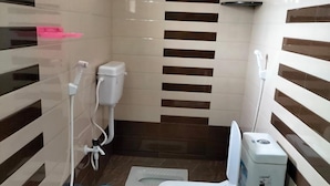 A compact bathroom with a toilet, a bidet, a small sink, and a blue bucket. - Ruby Home Stay (Sagara)