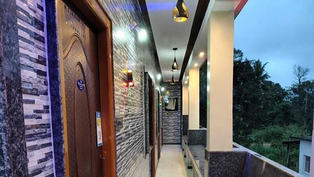 A corridor with a wooden door, a bench, and a railing overlooking greenery. - Ruby Home Stay (Sagara)