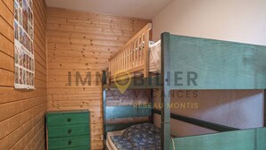 A wooden cabin room with bunk beds, a green dresser, and a poster on the wall. - Charmant appartement de 3 pièces au 1er étage de l'immeuble "Les Roches" à proximité du centre du vi (Chandolin)