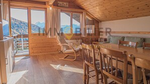 Eine Holzhütte mit Essbereich, Schaukelstuhl und einer Couch.
