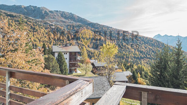 Blick auf einen Berg mit einer Holzterrasse, die auf ein Gebäude mit Balkon blickt.