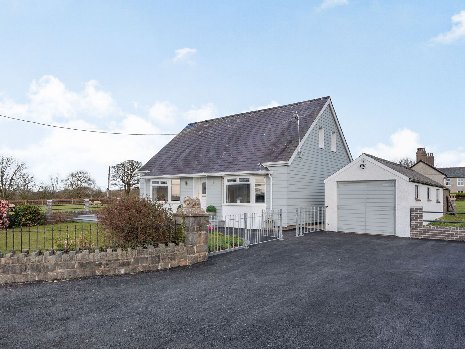 A single-story house with a grey roof, a garage, and a paved driveway.