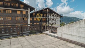 A multi-story wooden building with balconies, a sign reading "CANC RESEAU MONTS," and a mountainous backdrop. - Très agréable 2 pièces contemporain, idéal pour 2 à 4 personnes, situé dans une petite résidence de (St-Luc)