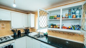 A kitchen with white cabinets, a black countertop, a stove, a sink, and a built-in washing machine.