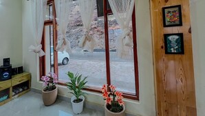 Un hall d’hôtel doté d’une grande fenêtre, d’un comptoir d’accueil en bois et de plantes en pot.