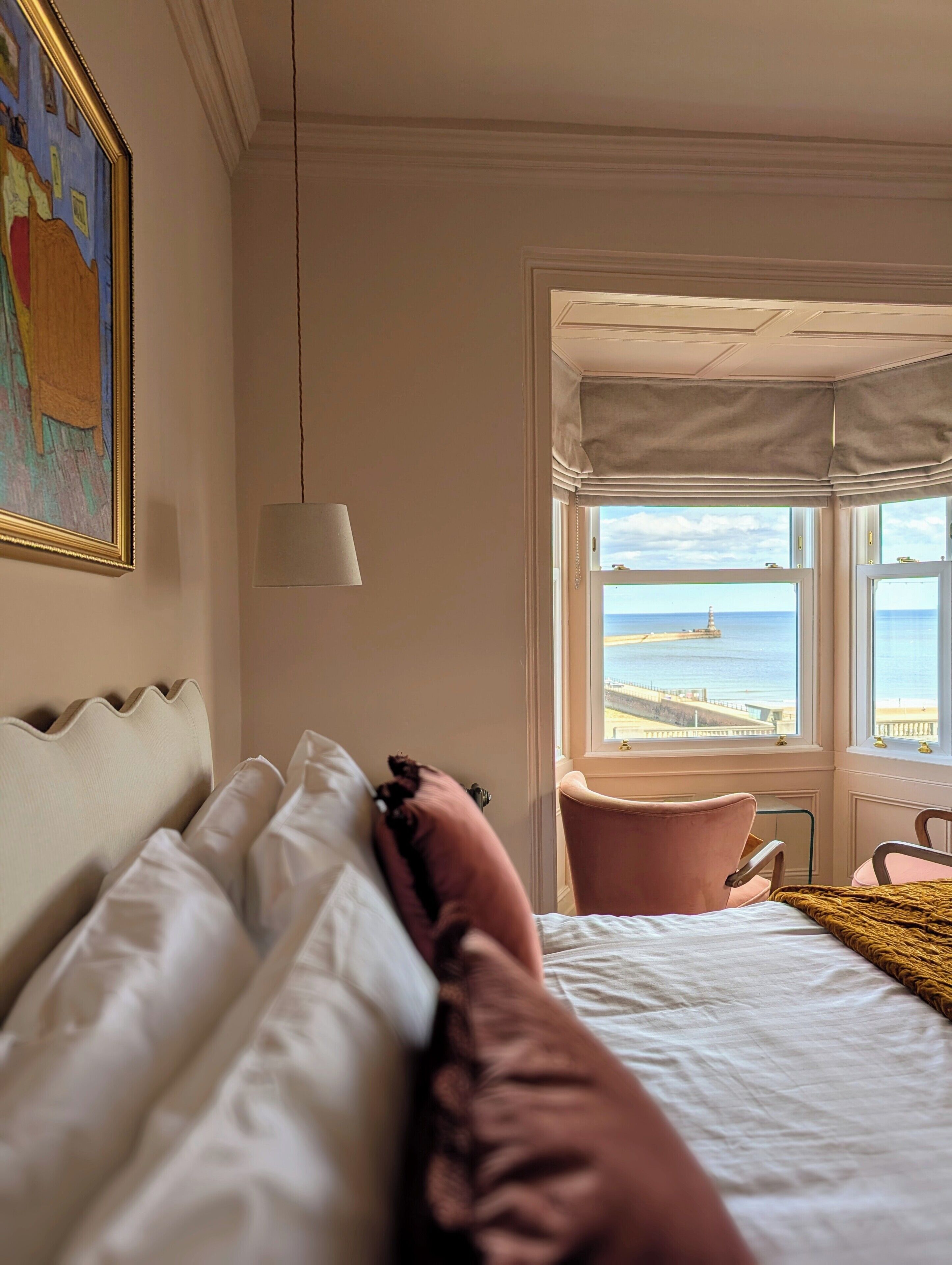 Une chambre d’hôtel avec un lit, une chaise, un tableau et une vue sur la mer.