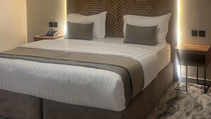 A modern hotel room with a large bed, a ceiling fan, an air conditioning unit, and a patterned wall. - Anaf Hotel (Madinah)