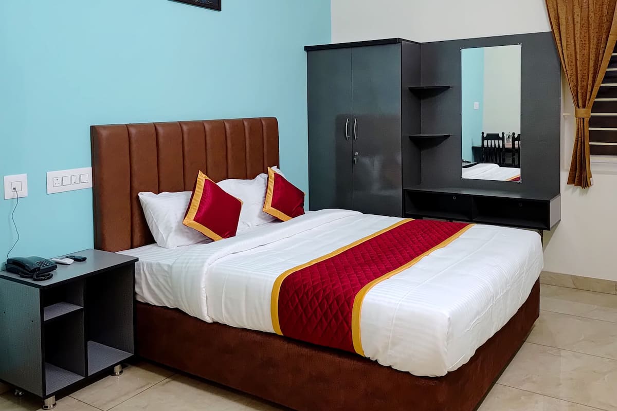 Une chambre d’hôtel bien rangée, avec un lit, une table de chevet, une armoire et un ventilateur de plafond.