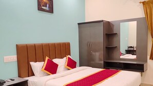 Une chambre d’hôtel comprenant un lit, une armoire, une table de chevet et un miroir fixé au mur.