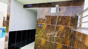 Un baño moderno con ducha, un cartel que indica baño de hombres y una zona de piscina con césped artificial.