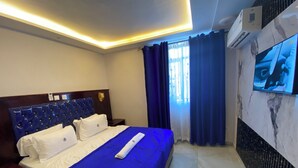 Habitación de hotel con cama, televisor de pantalla plana montado en la pared y aire acondicionado.